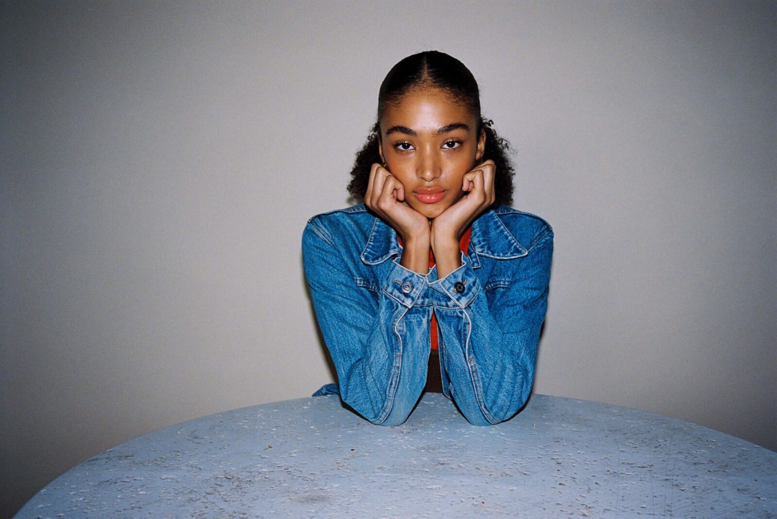 Young woman in denim jacket resting chin on hands
