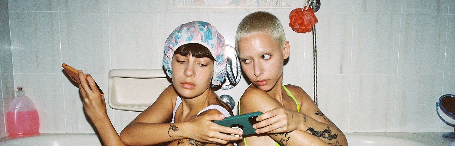 Two people sitting back-to-back in bathtub