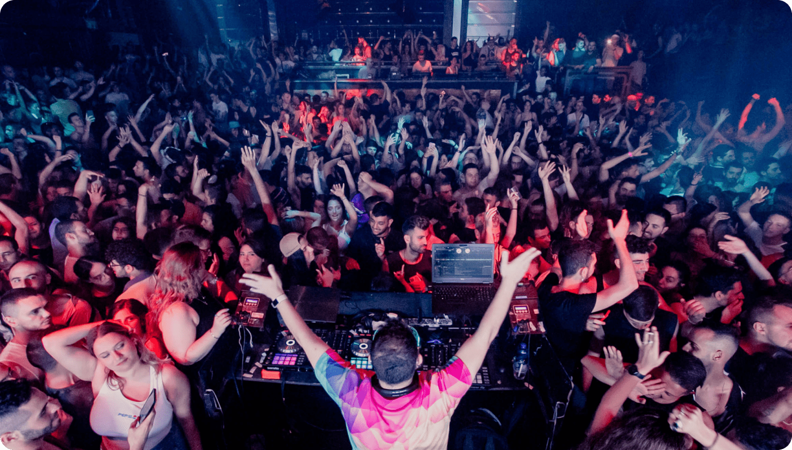 DJ performing for crowded energetic nightclub dance floor
