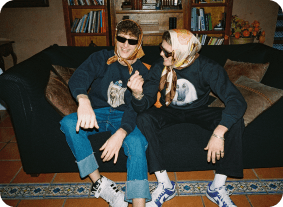 Two friends laughing on couch wearing headscarves