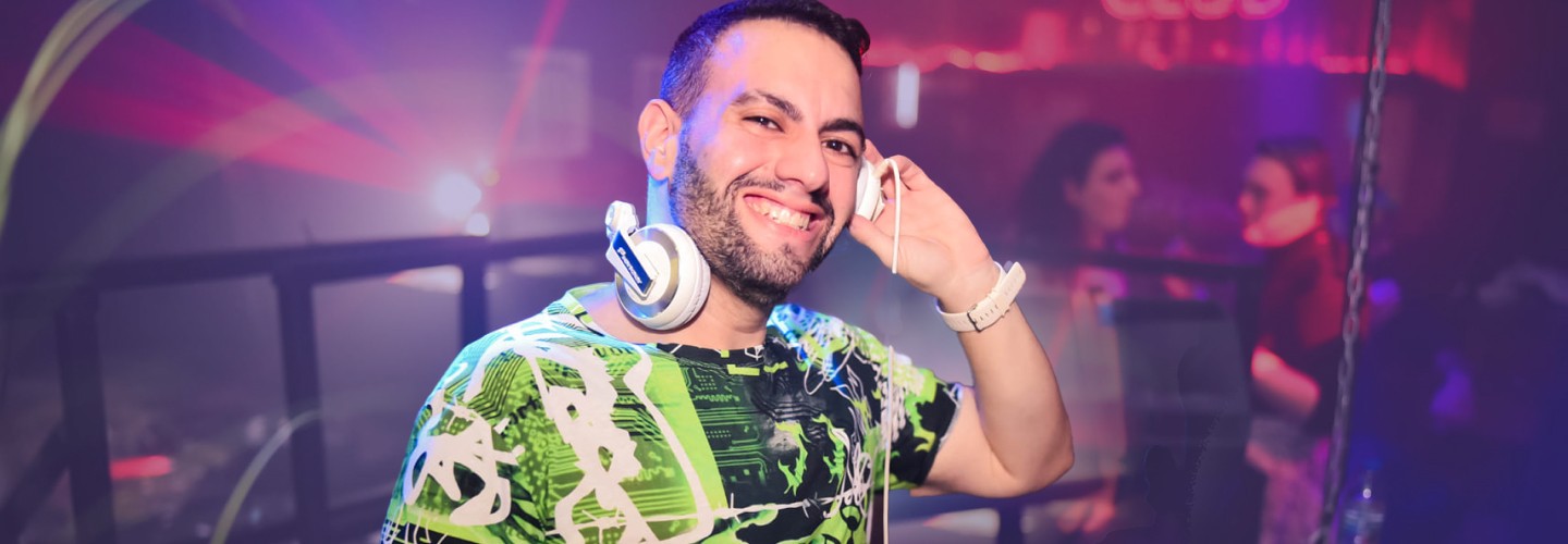 Smiling male DJ with headphones at nightclub