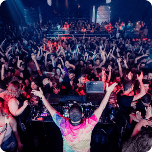 DJ performing for large dancing crowd at nightclub