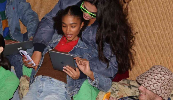 Group of friends using devices and smiling