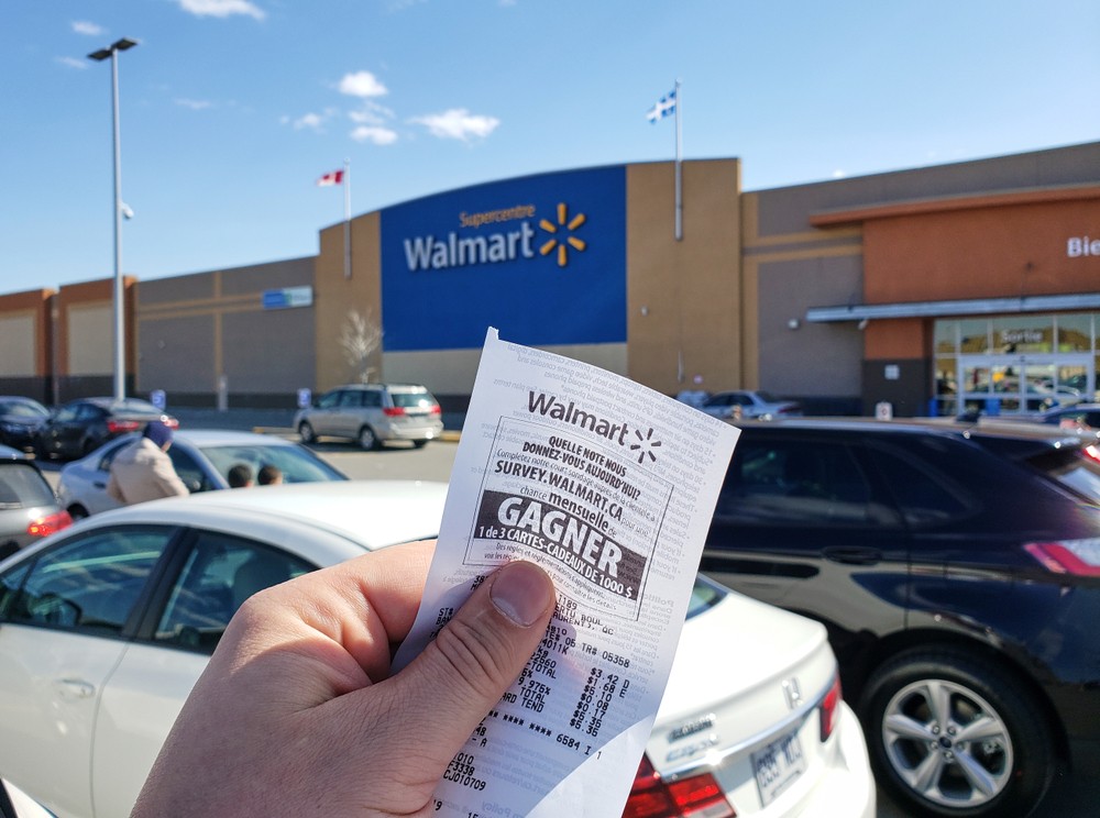 Hand holding Walmart receipt outside Walmart store