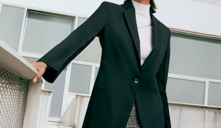 Confident woman in black blazer and plaid skirt
