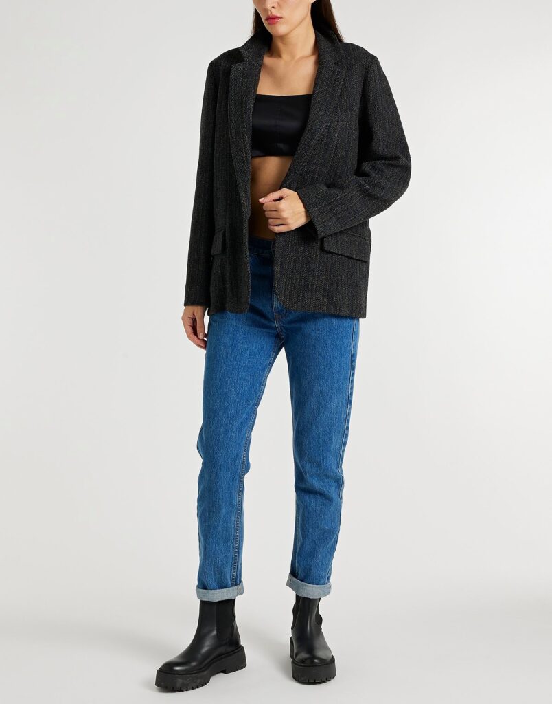 Woman wearing black blazer, blue jeans, black boots
