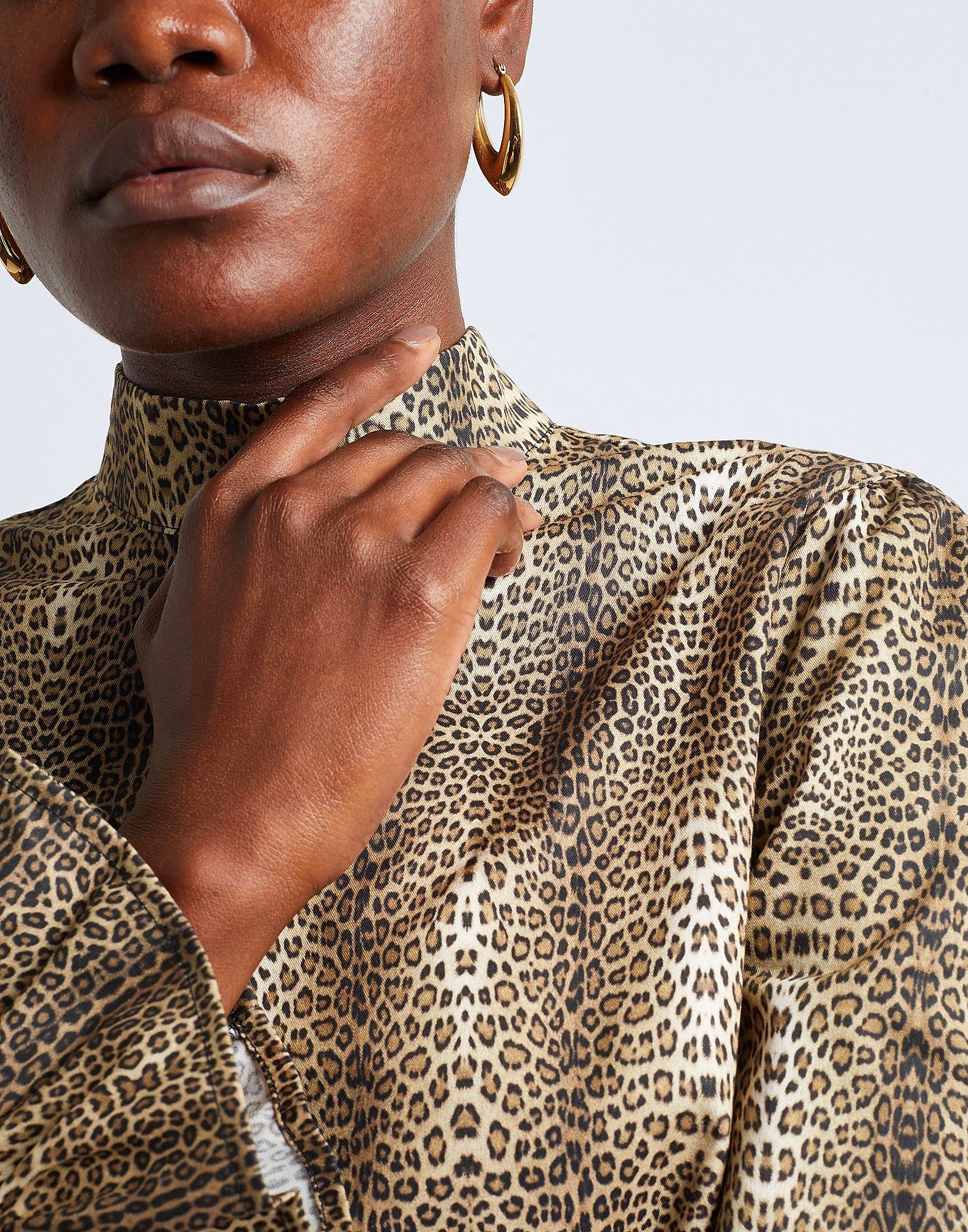 Woman wearing leopard print top and gold hoop earrings