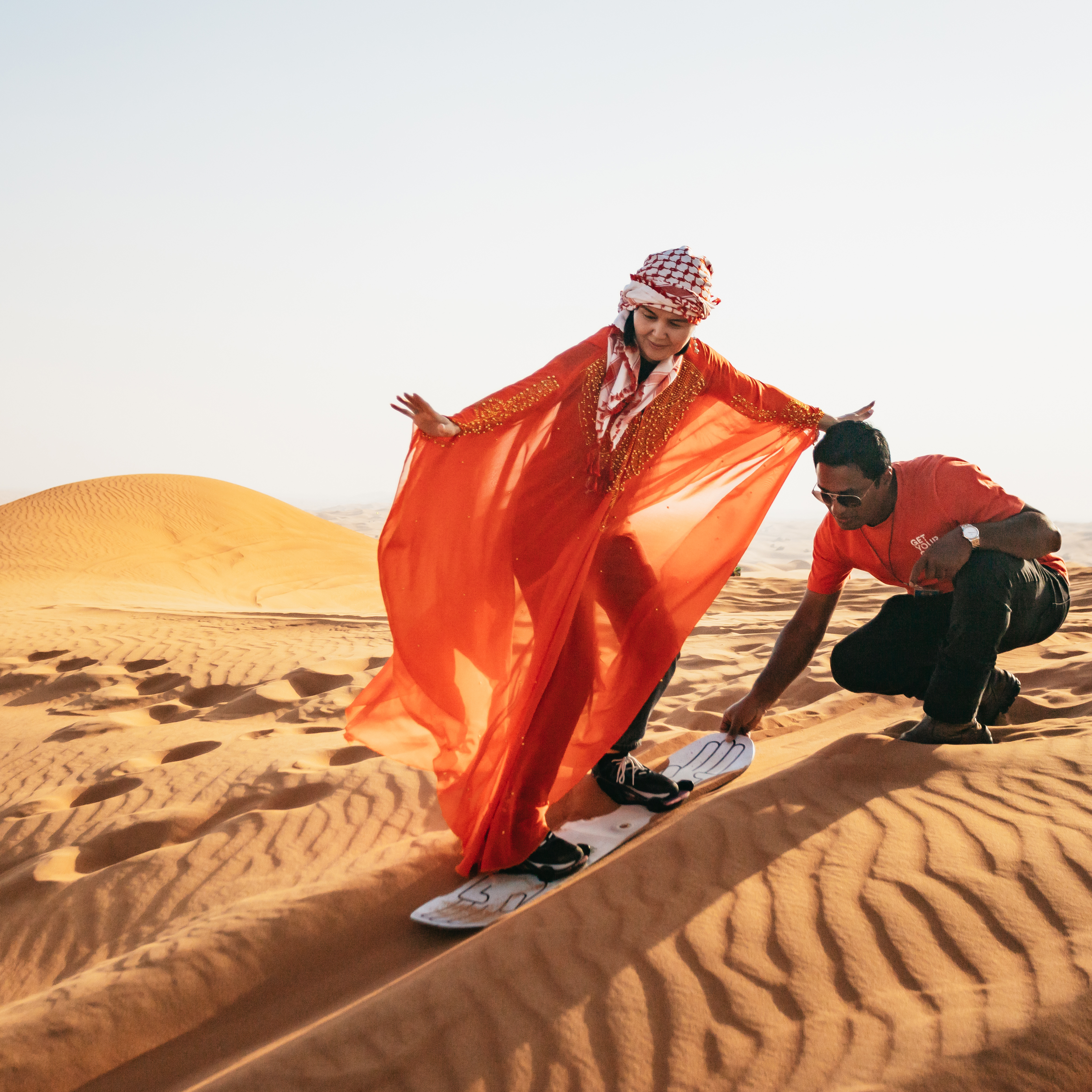 Woman sandboarding in flowing red robe