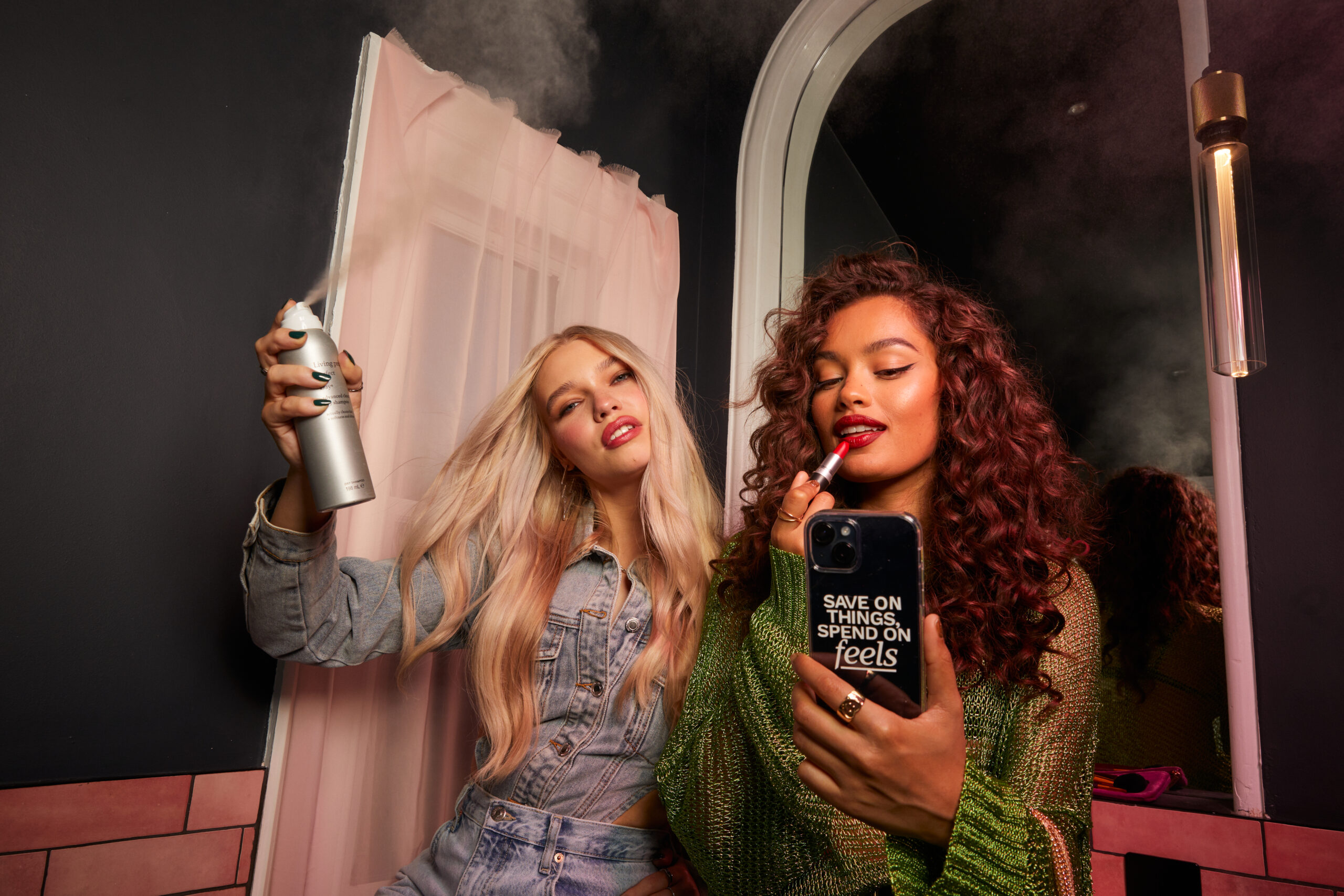 Two women applying makeup and hair spray