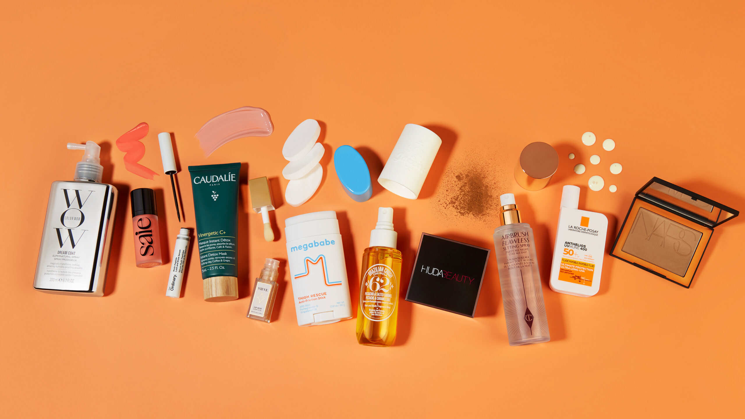 Various skincare and makeup products on orange background