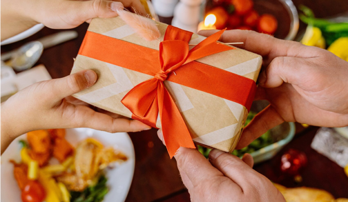 Hands exchanging gift wrapped with orange ribbon