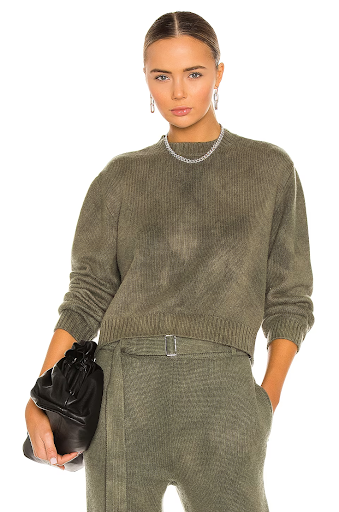 Woman wearing olive green sweater and pants holding purse
