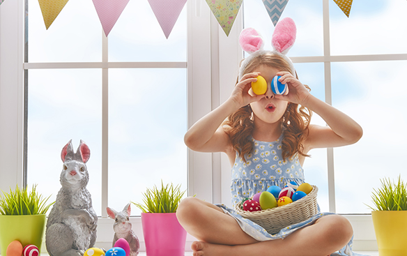 Girl with bunny ears holding colorful Easter eggs