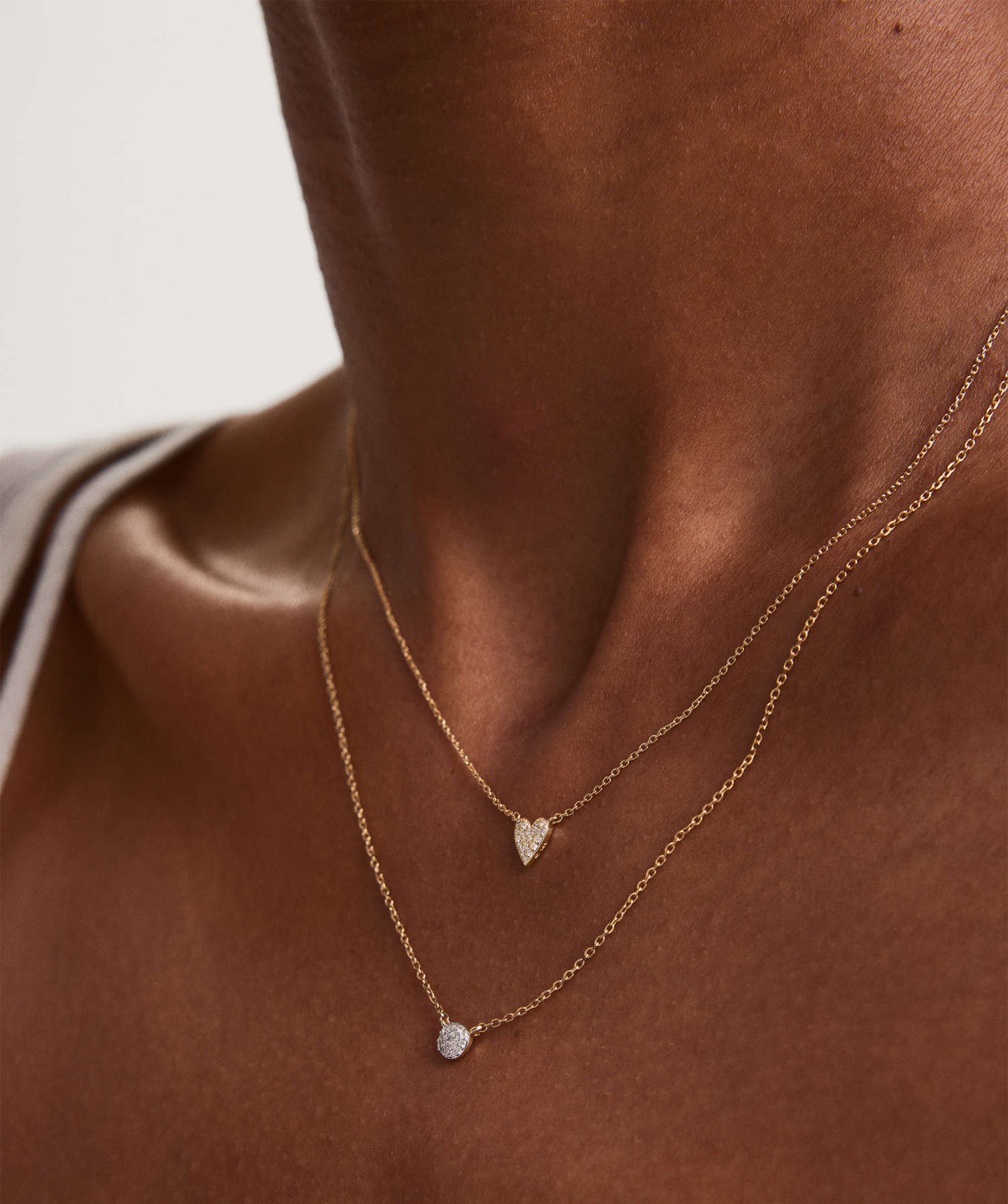 Two delicate gold necklaces with diamond pendants