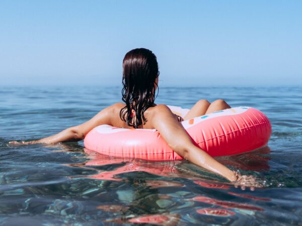 Person relaxing on pink float in clear water