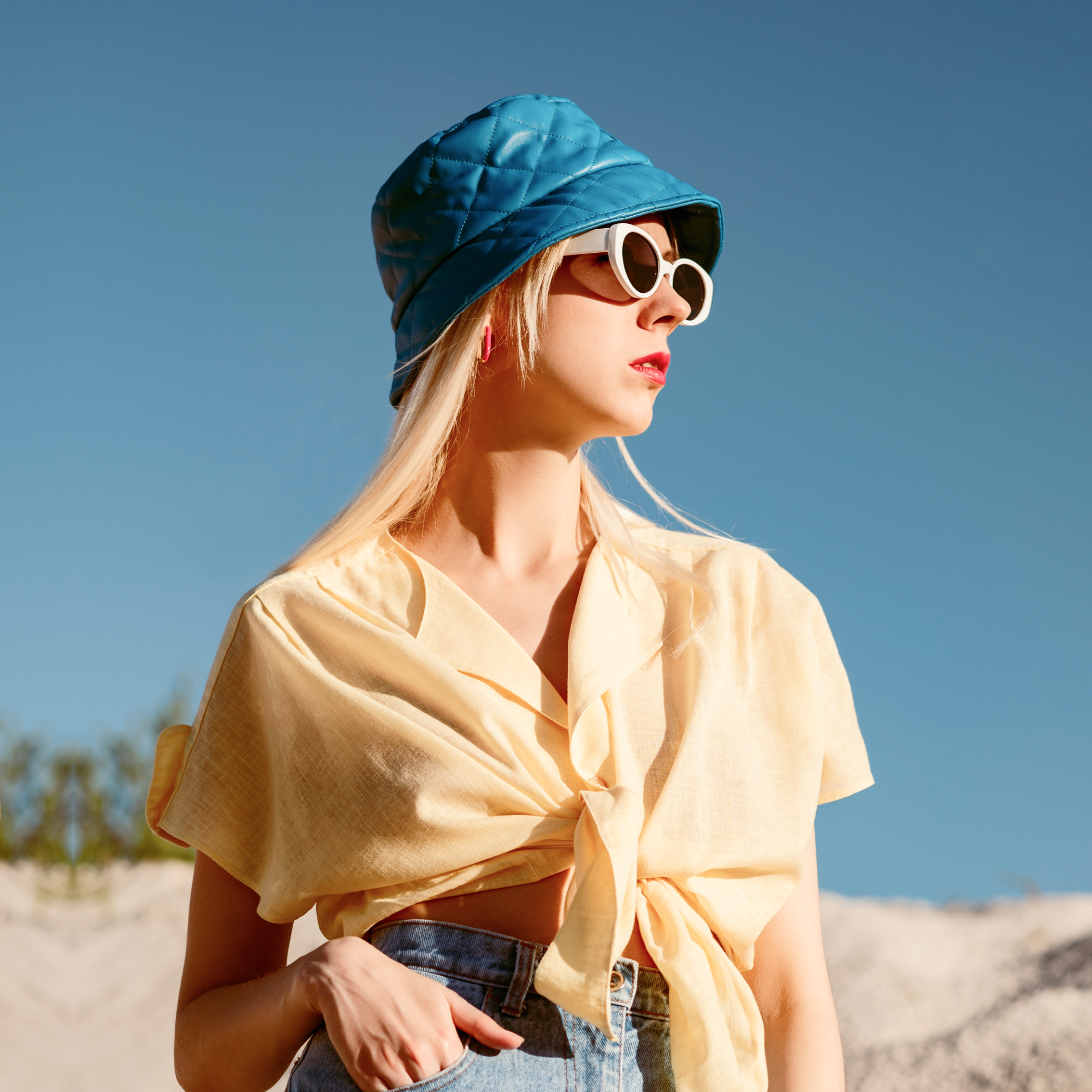 Woman in yellow shirt, blue hat, sunglasses