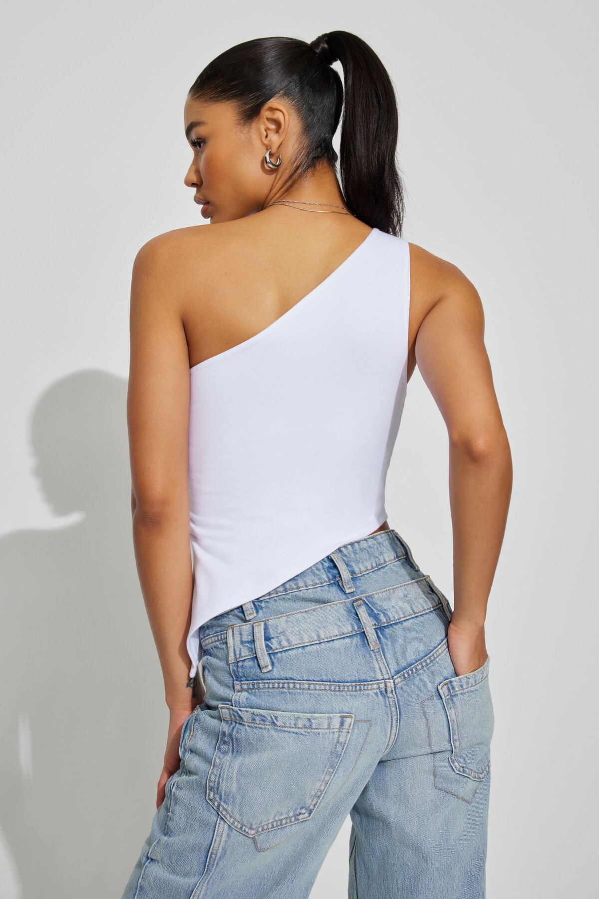 Woman in white one-shoulder top and blue jeans