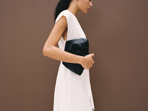 Woman in white dress holding black clutch purse