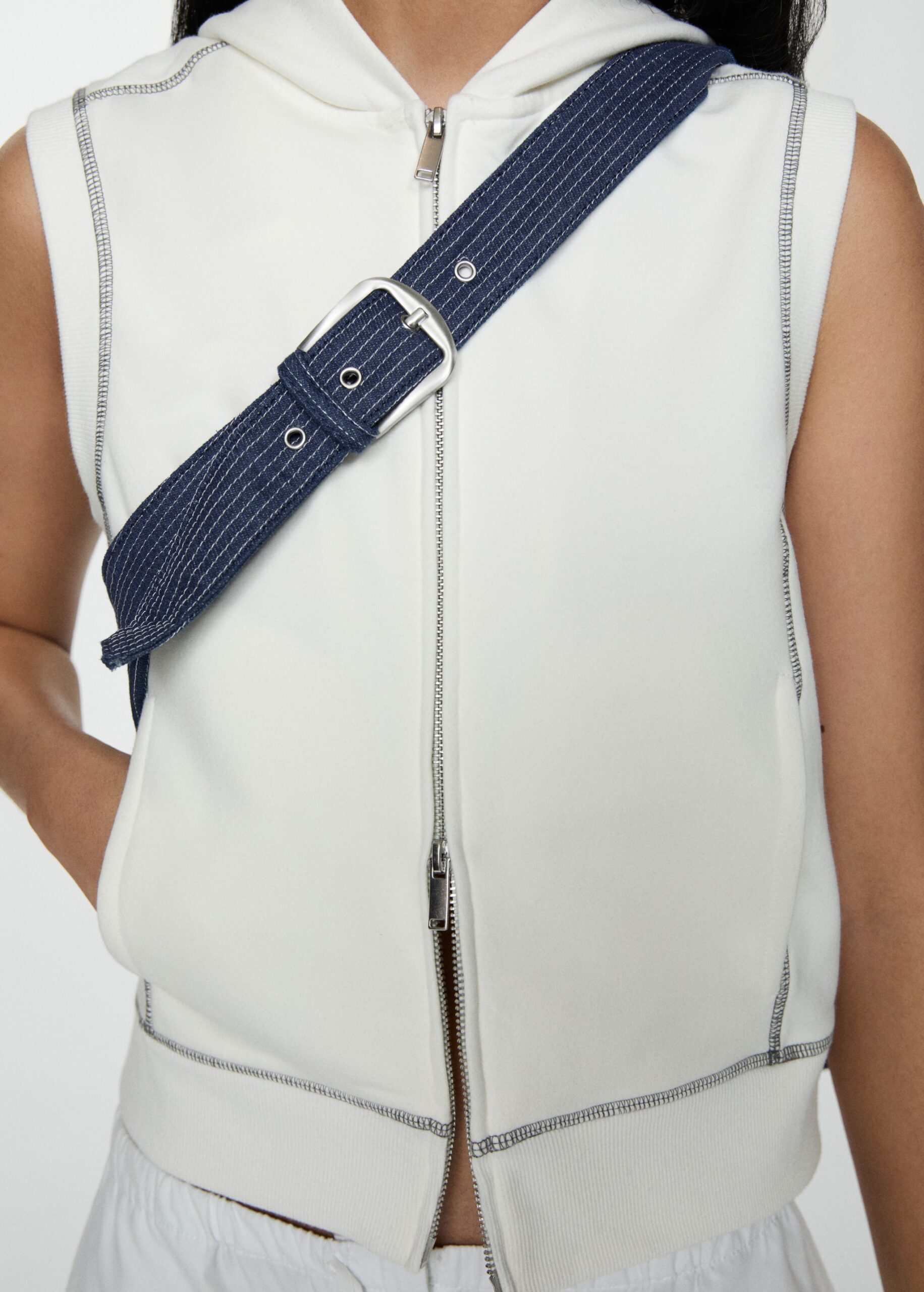 Close-up of person wearing white sleeveless hoodie and blue strap