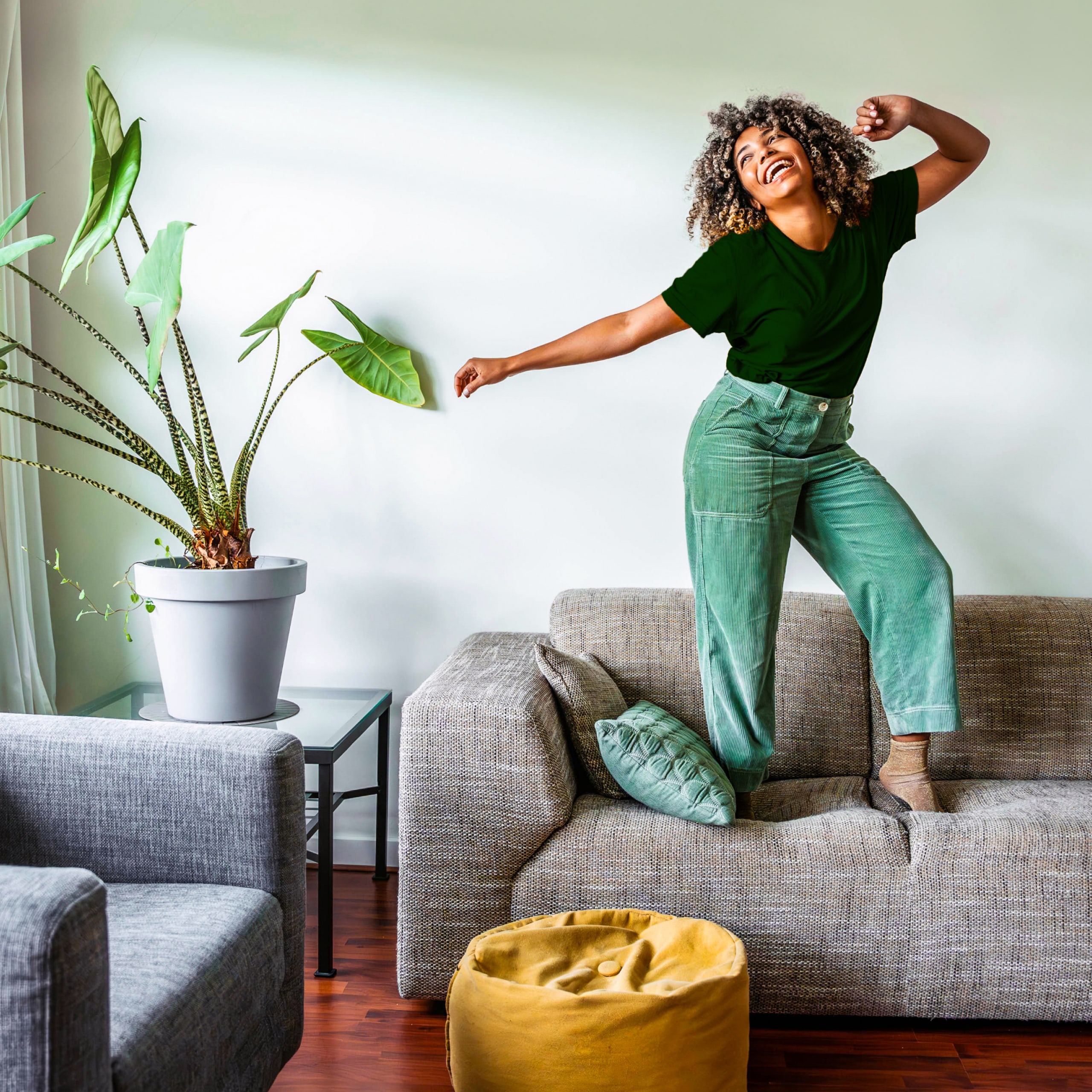Joyful woman dancing on sofa in bright living room