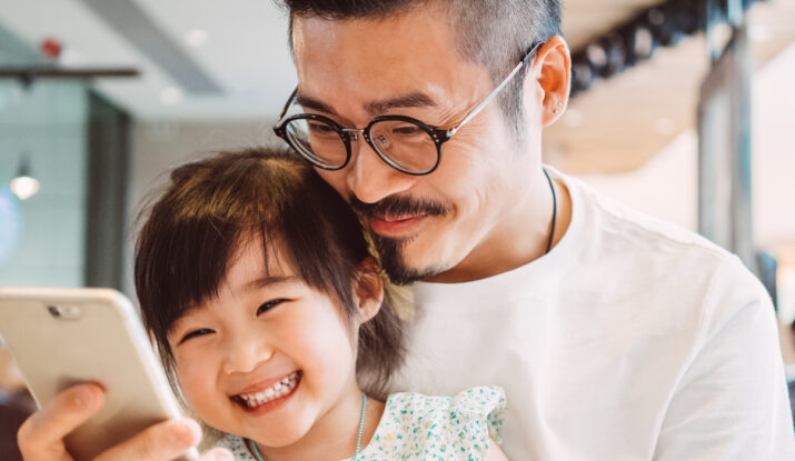 Father and daughter smiling at smartphone together
