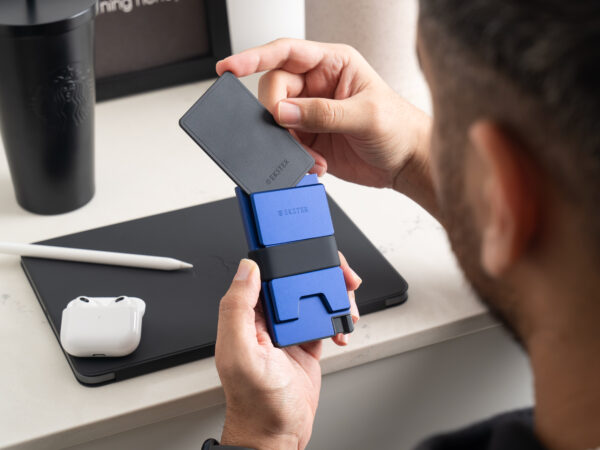 Man holding blue cardholder and black card at desk