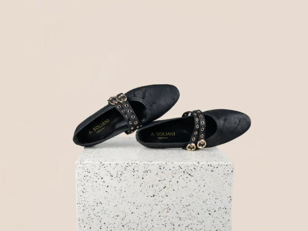 Black studded flats on terrazzo pedestal