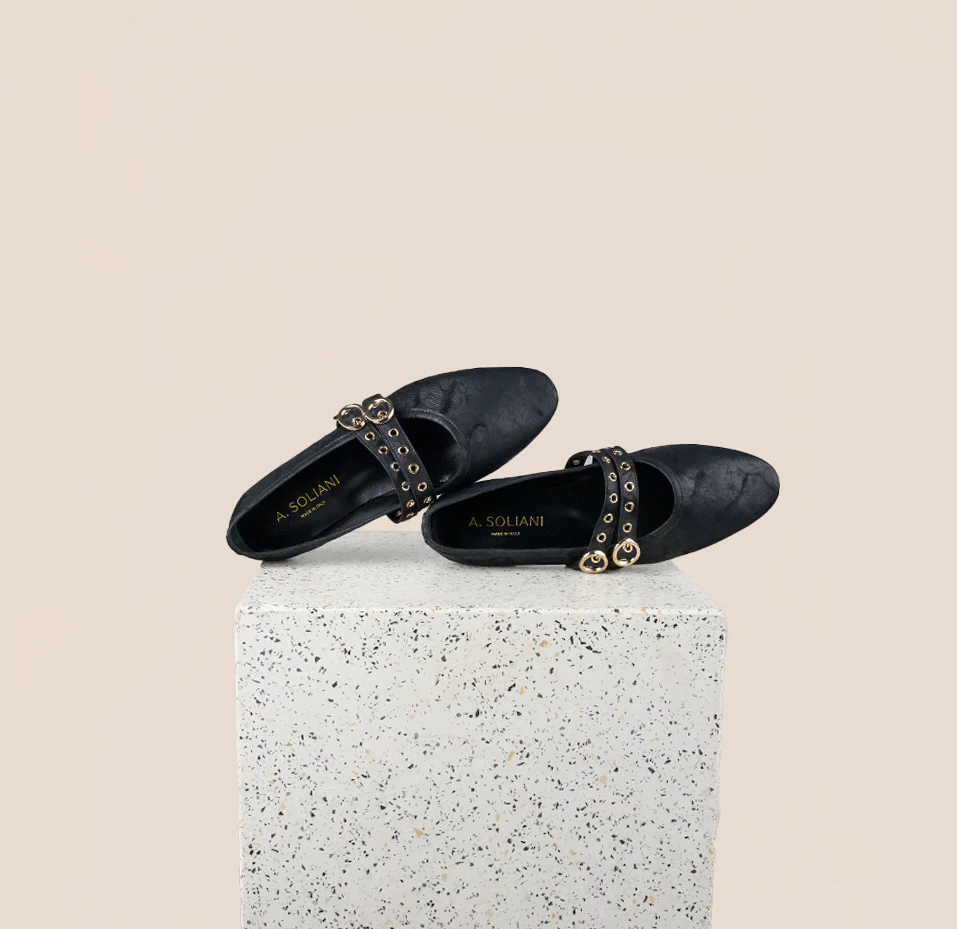 Black studded flats on terrazzo pedestal