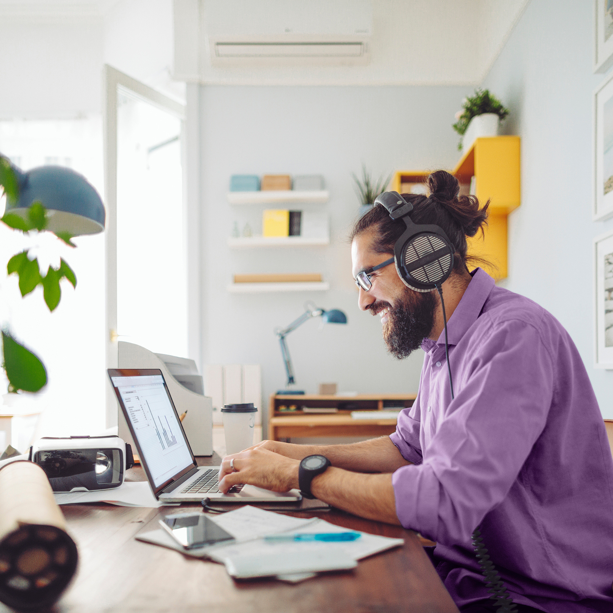 Man smiling working on laptop wearing headphones