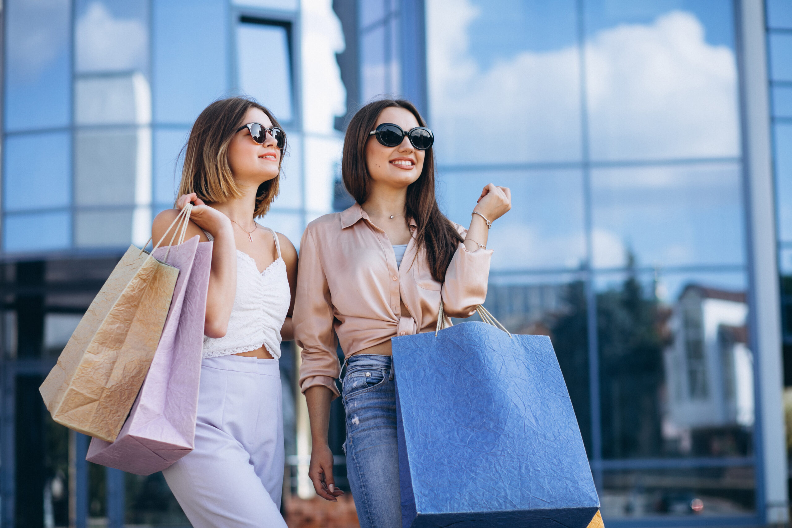 Two women smiling with shopping bags outside