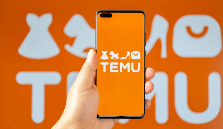 Hand holding smartphone with Temu app logo