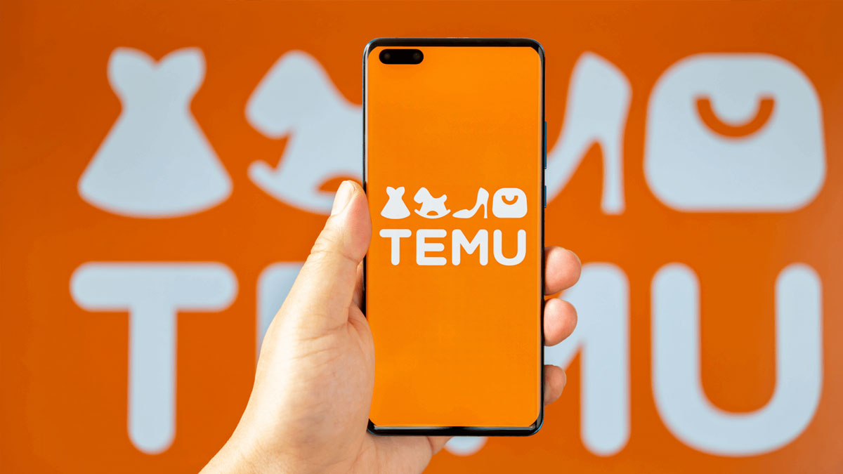 Hand holding smartphone with Temu app logo