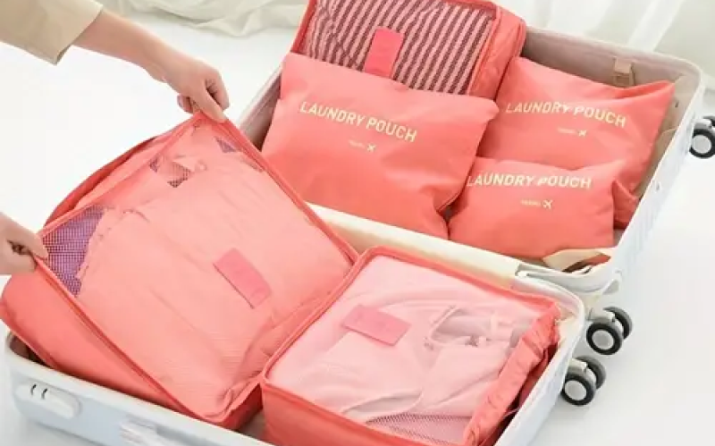 Open suitcase with coral laundry pouches and organized clothes