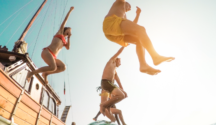 People jumping off wooden boat into sea