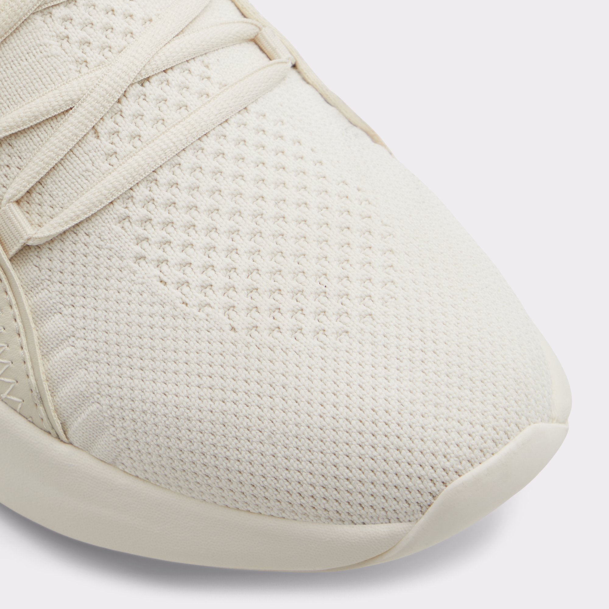 Close-up of cream knitted sneaker toe with laces