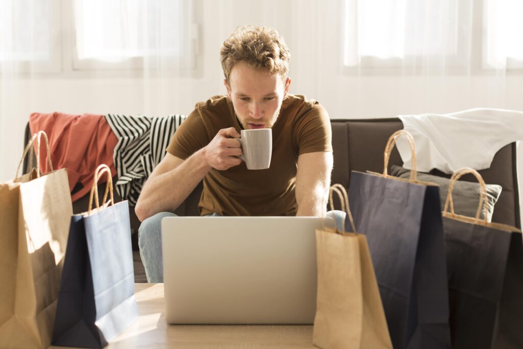 Man shopping online with coffee and bags nearby
