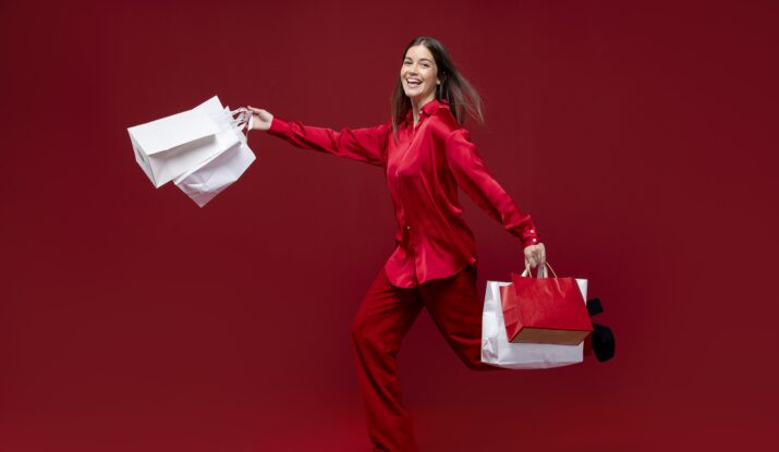 Happy woman in red holding shopping bags