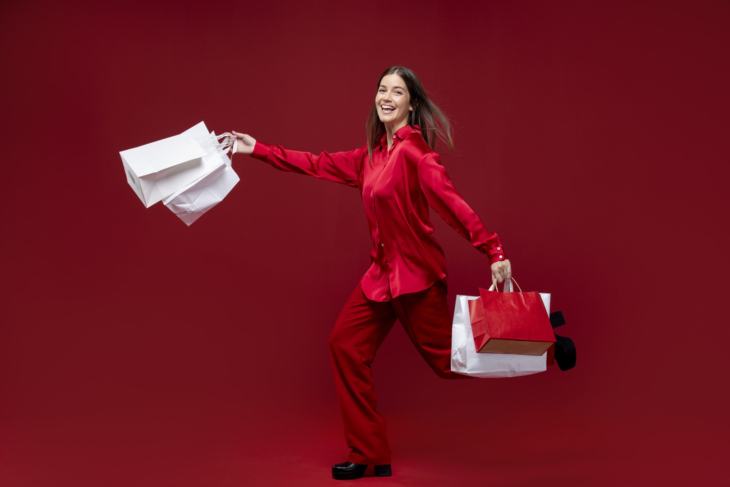 Happy woman in red holding shopping bags