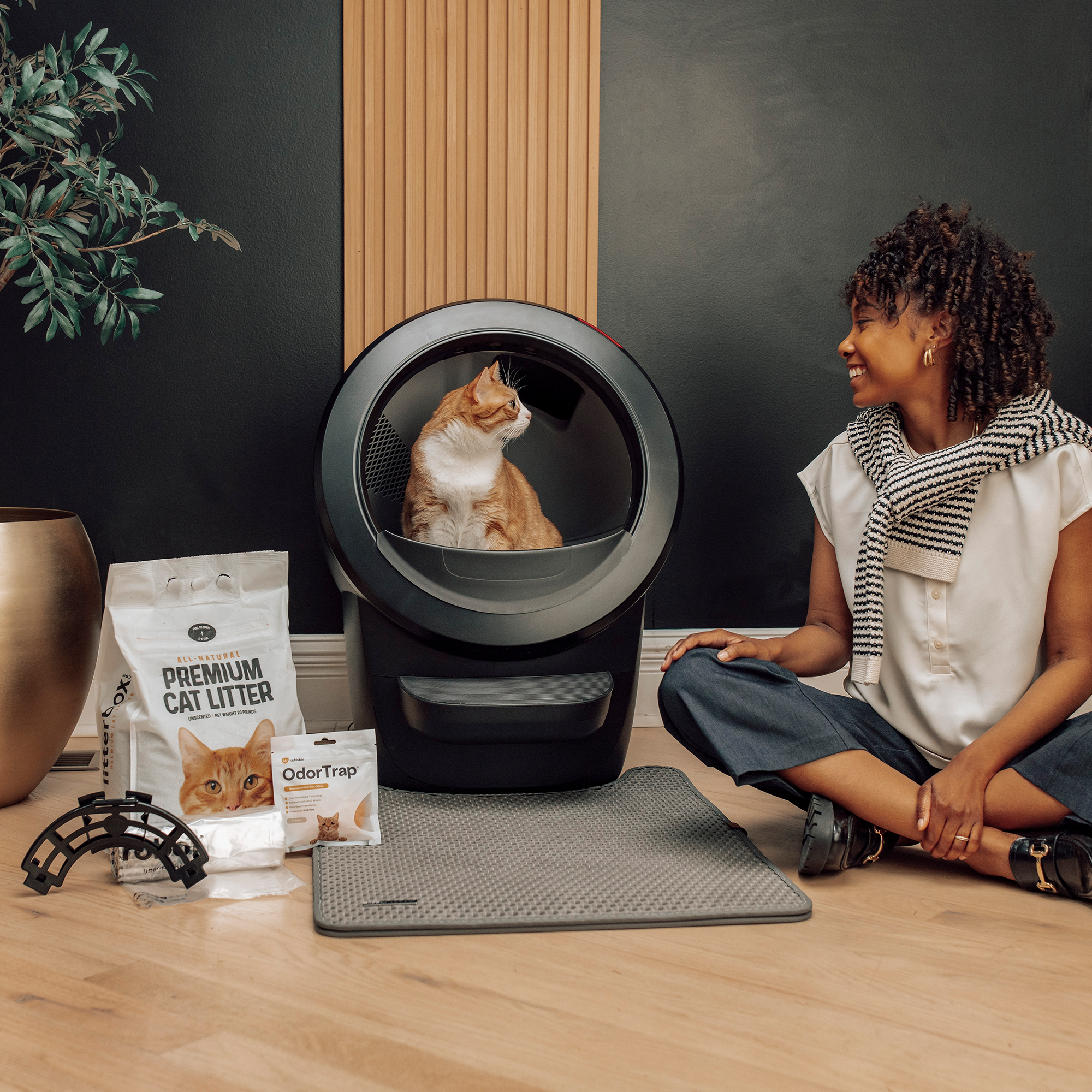Woman sitting near cat in automated litter box