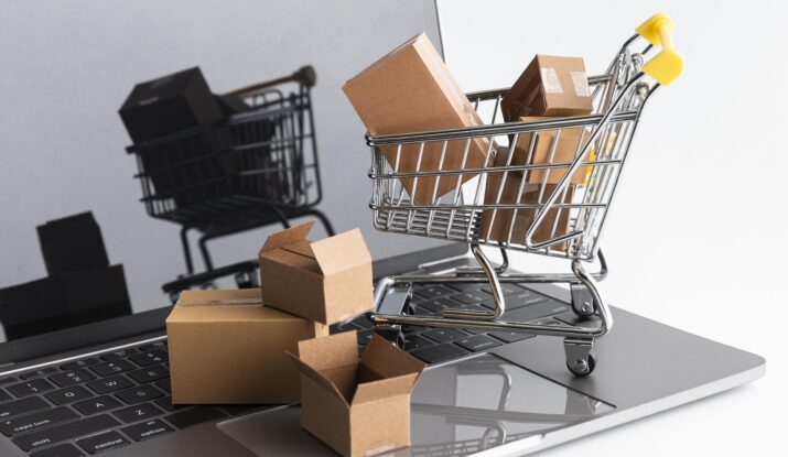 Mini shopping cart with packages on laptop keyboard