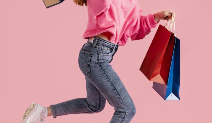 Woman jumping joyfully with colorful shopping bags