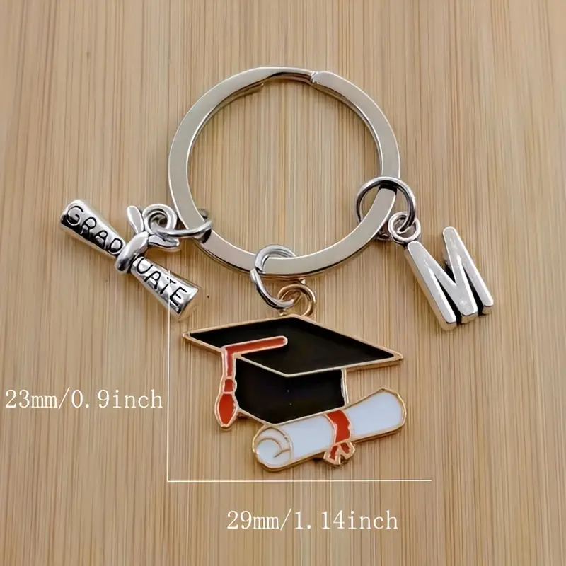 Keychain with graduation cap, diploma, and letter M charms