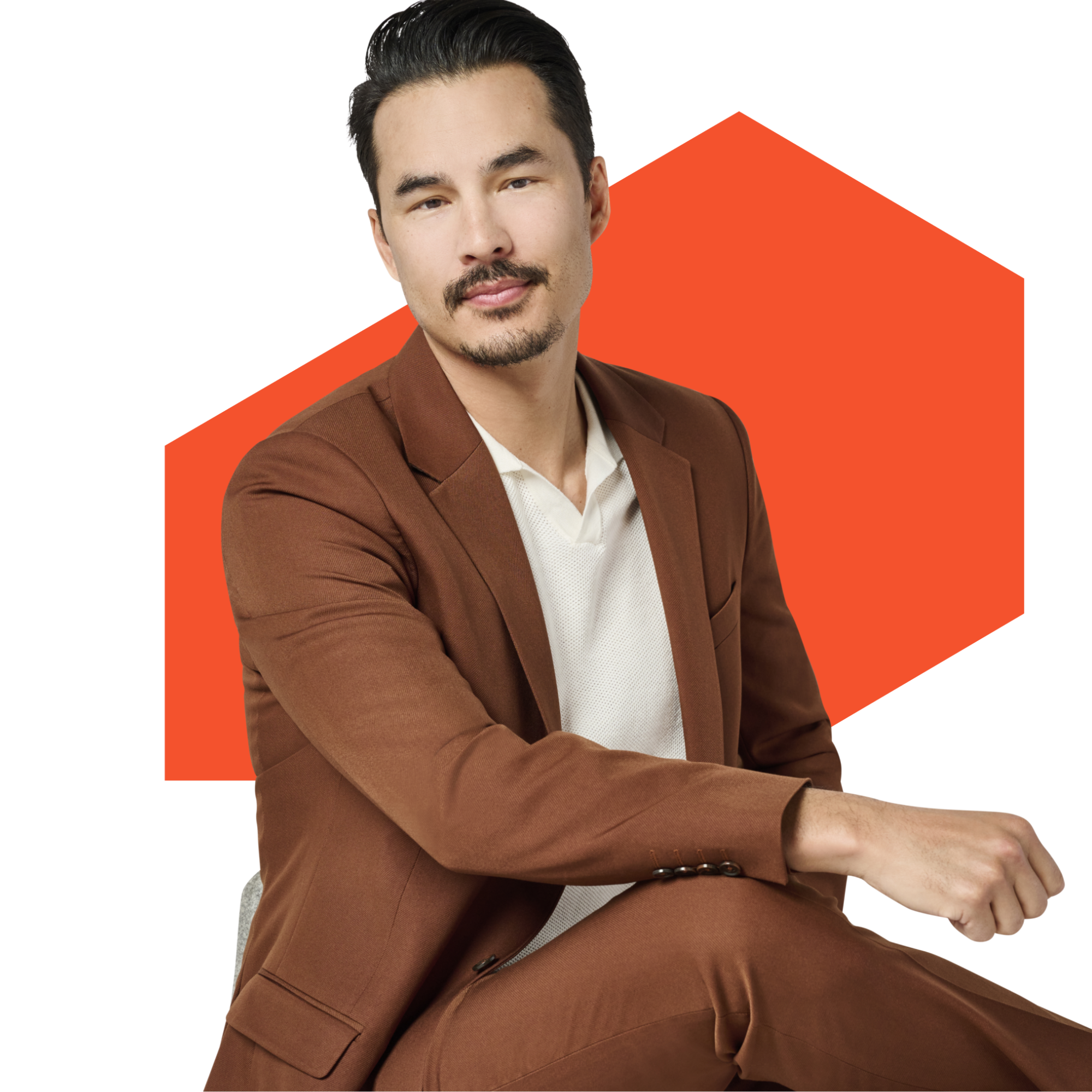 Man in brown suit seated with orange background