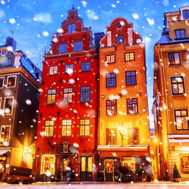 Colorful old buildings with snow falling at dusk