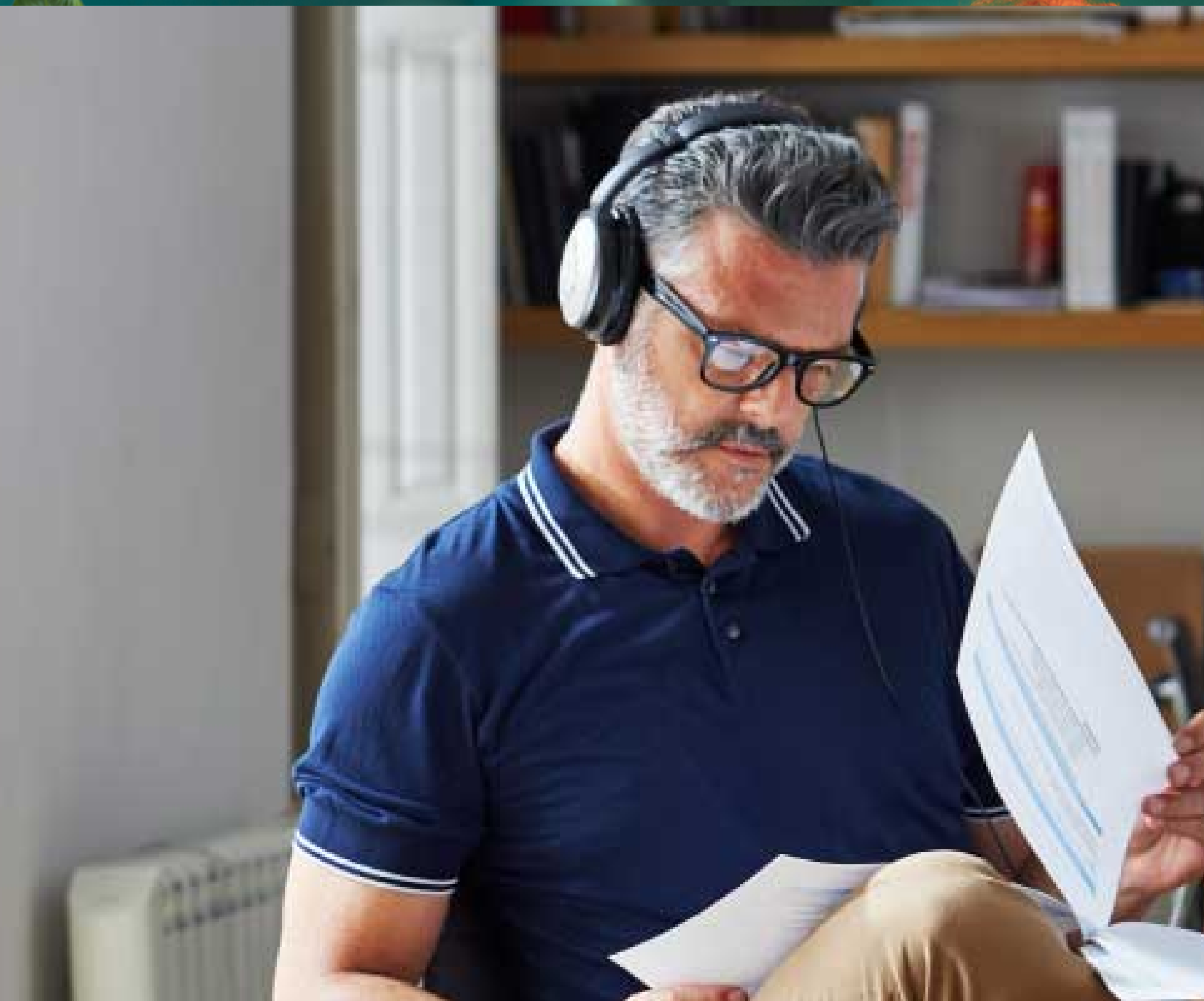 Man with headphones reviewing documents indoors