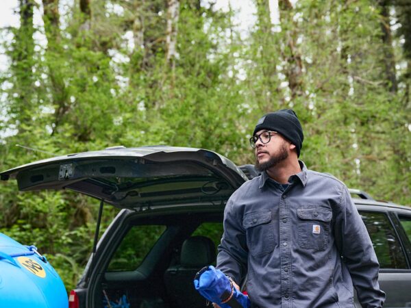 Man preparing for outdoor activity by open car trunk