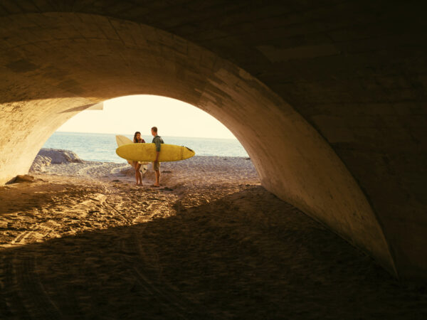 Couple with surfboards under beach tunnel