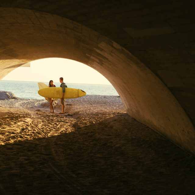 Surfers standing under tunnel on sandy beach