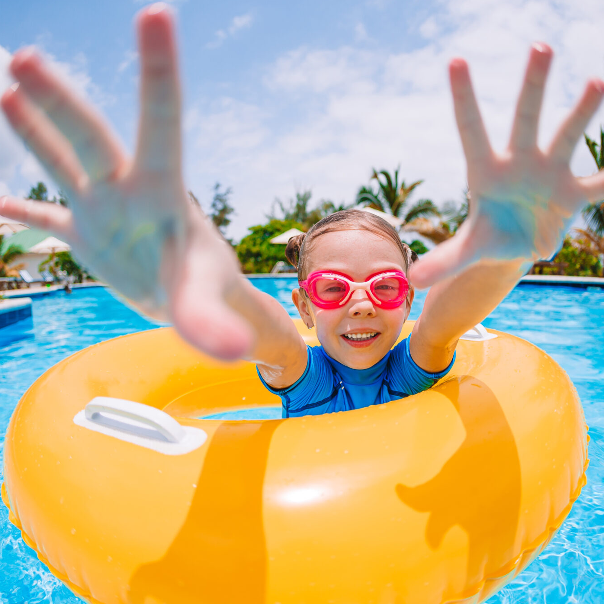 Child in pink goggles reaching out from yellow float
