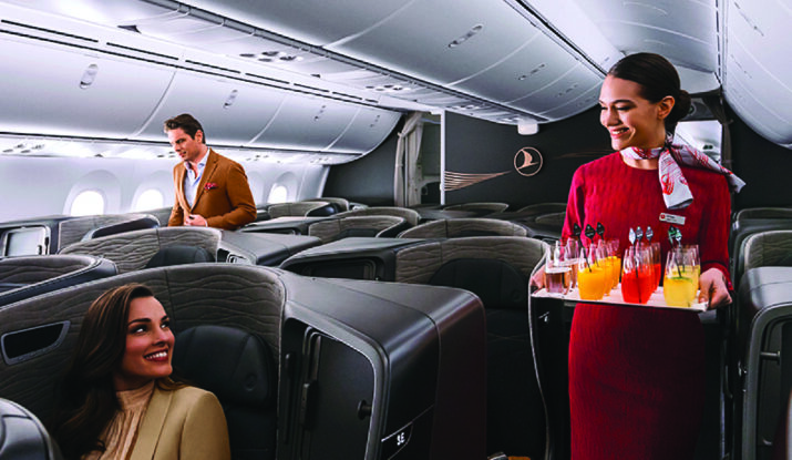 Flight attendant serving drinks in first class cabin